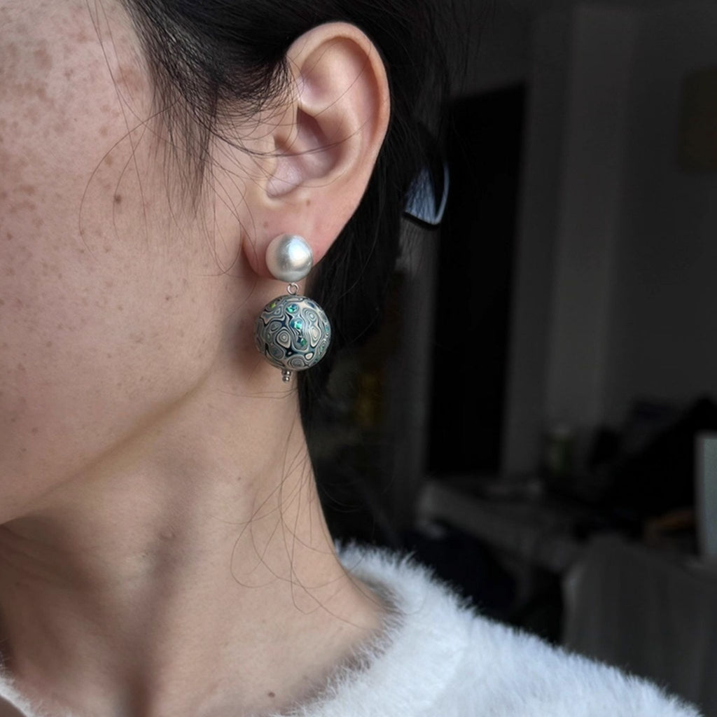 Close-up of an ear wearing a pearl earring with a dark background