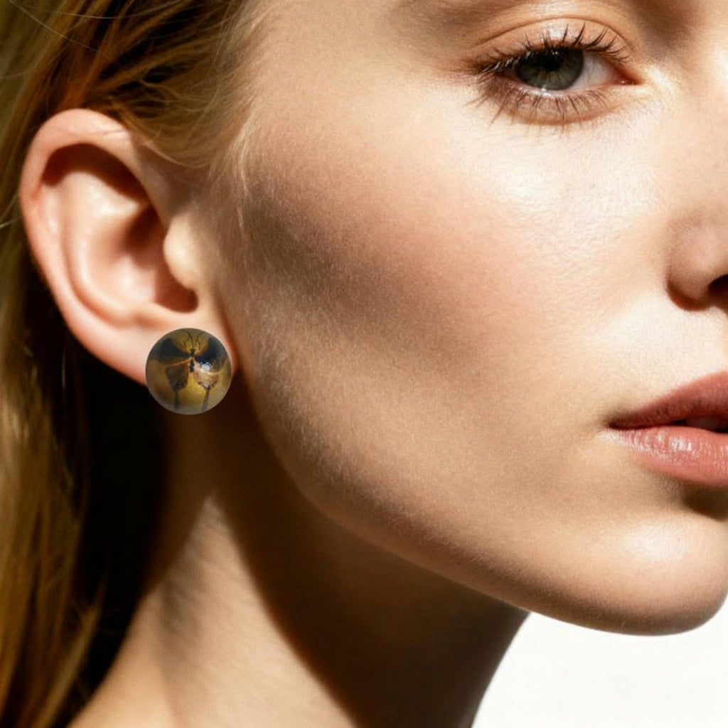 Close-up of a woman wearing a gold earring with a blue gemstone.