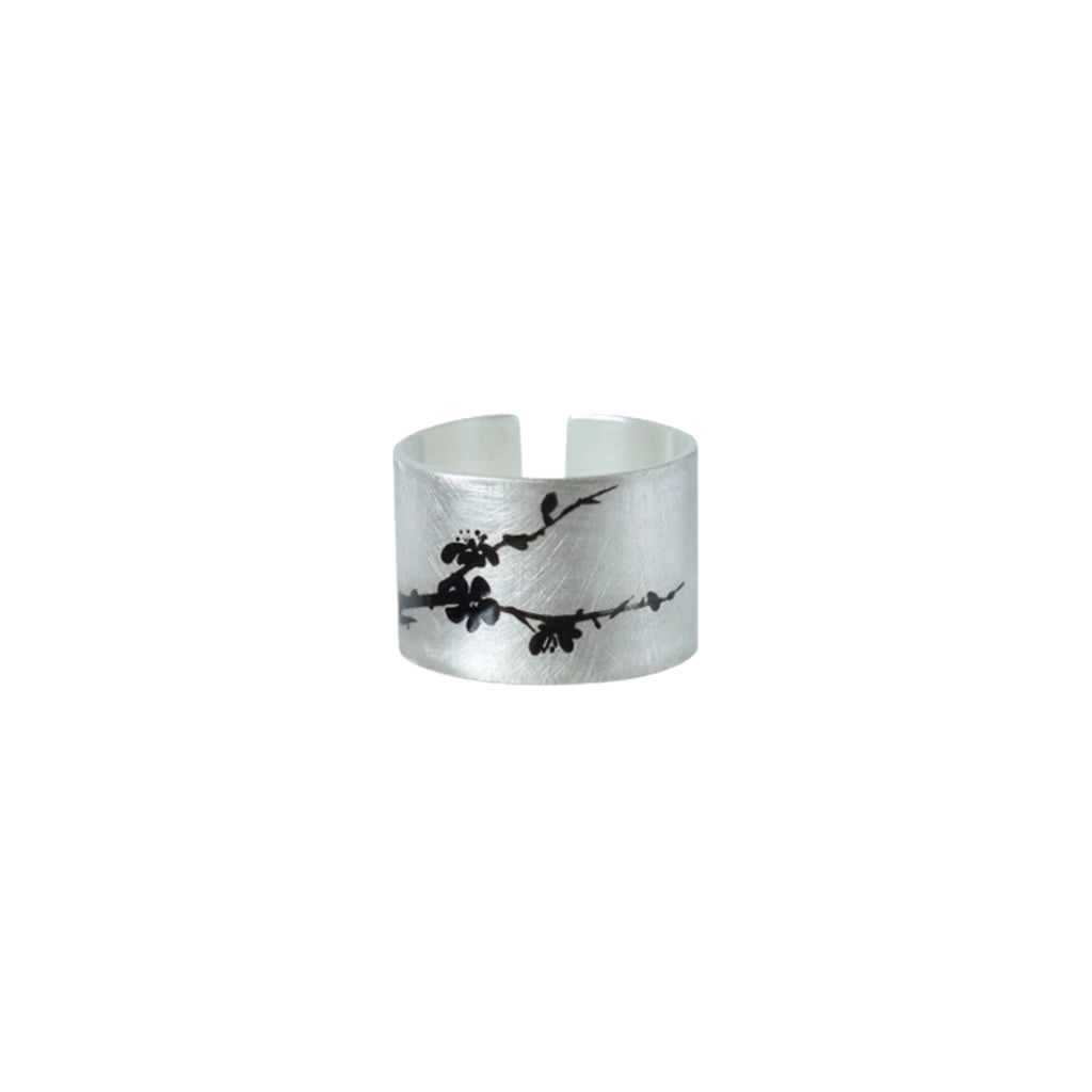 Silver ring with black floral design on a white background