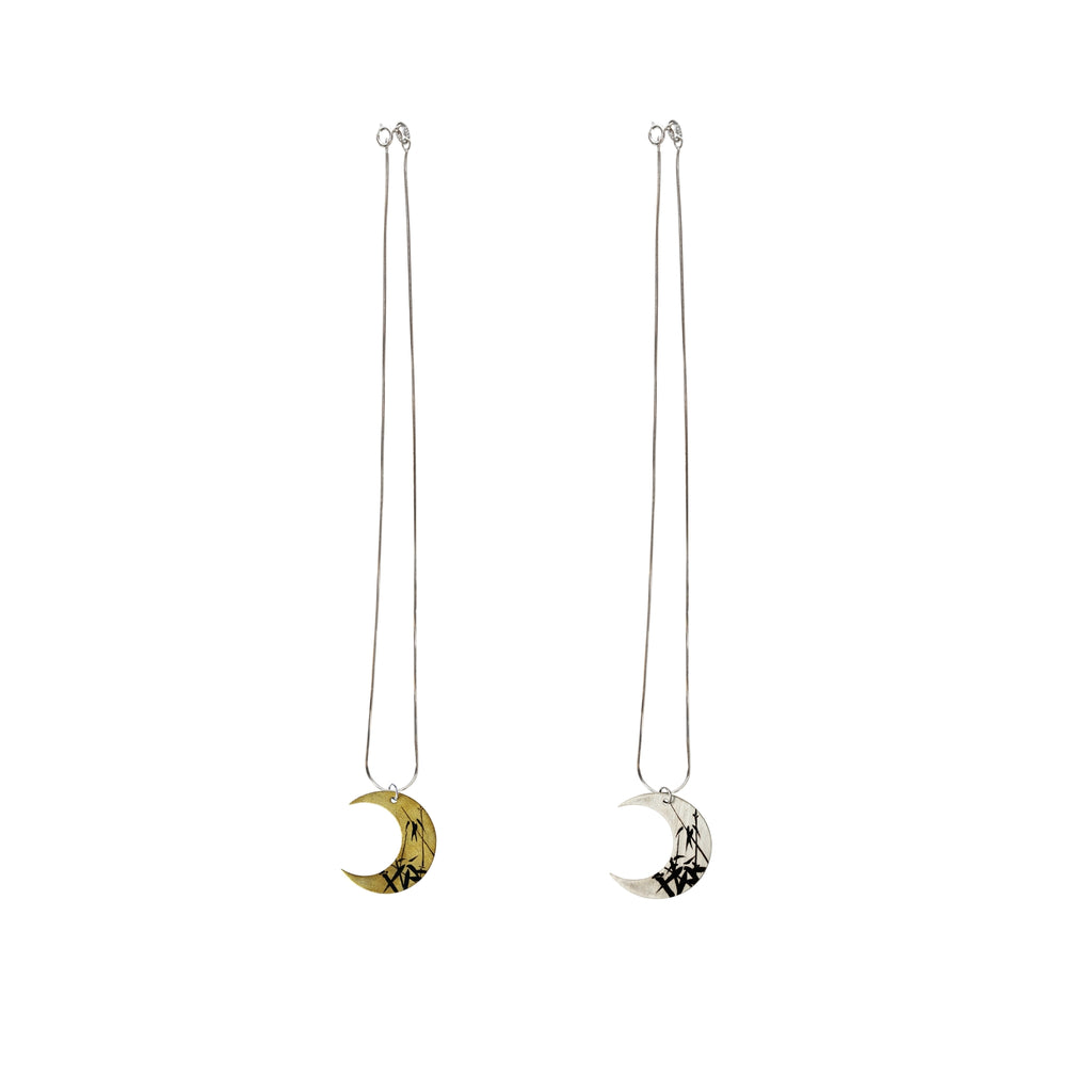 Two moon-shaped pendant necklaces on white background