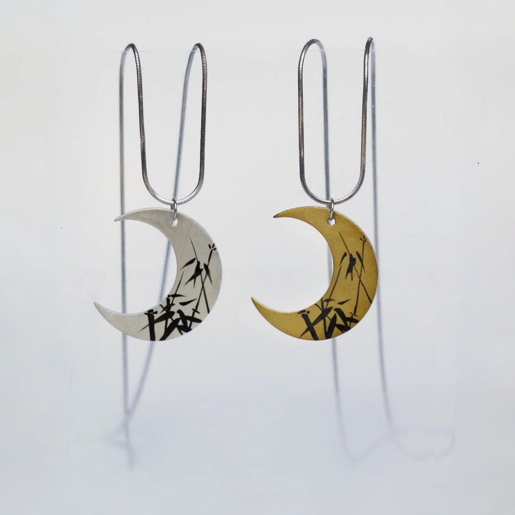 Pair of moon-shaped earrings with bamboo design on a white background