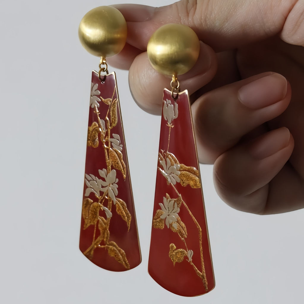 Red earrings with gold floral patterns held by a hand against a gray  LacLume Earrings Summer Jasmine Plant Pattern Jewelry Handmade Lacquer Jewelrybackground