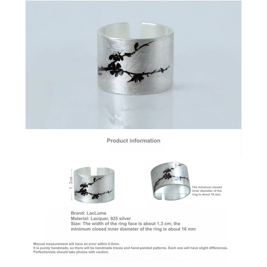 Silver cuff bracelet with black floral design on a light gray background