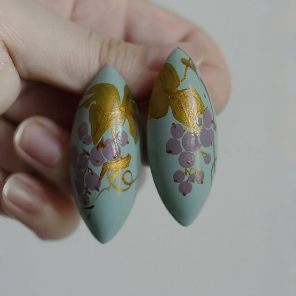 Two decorative items with gold and purple designs held by a hand against a neutral background LacLume Handcrafted Lacquer Earrings Purple Berry Bubbles Niche Daily Style