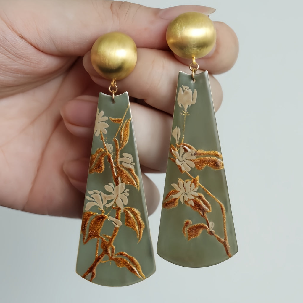 Gold and green earrings with floral design held by a hand against a neutral background LacLume Earrings Summer Jasmine Plant Pattern Jewelry Handmade Lacquer Jewelry
