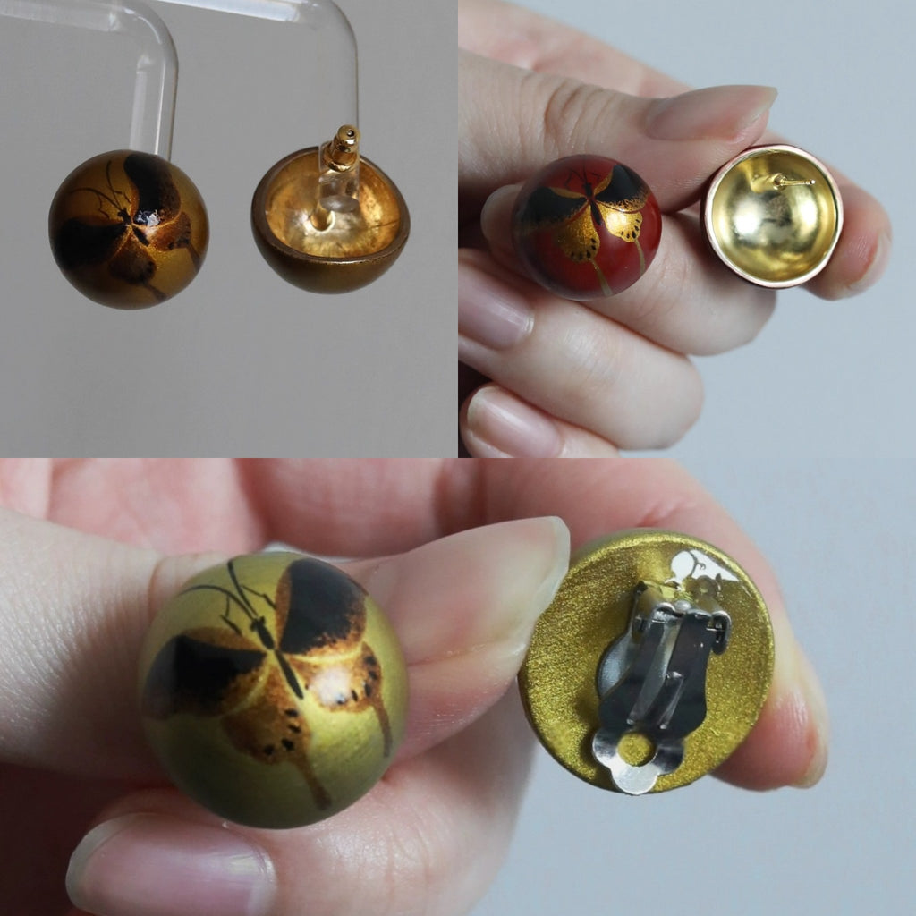 Gold and red earrings with intricate designs held by a hand.