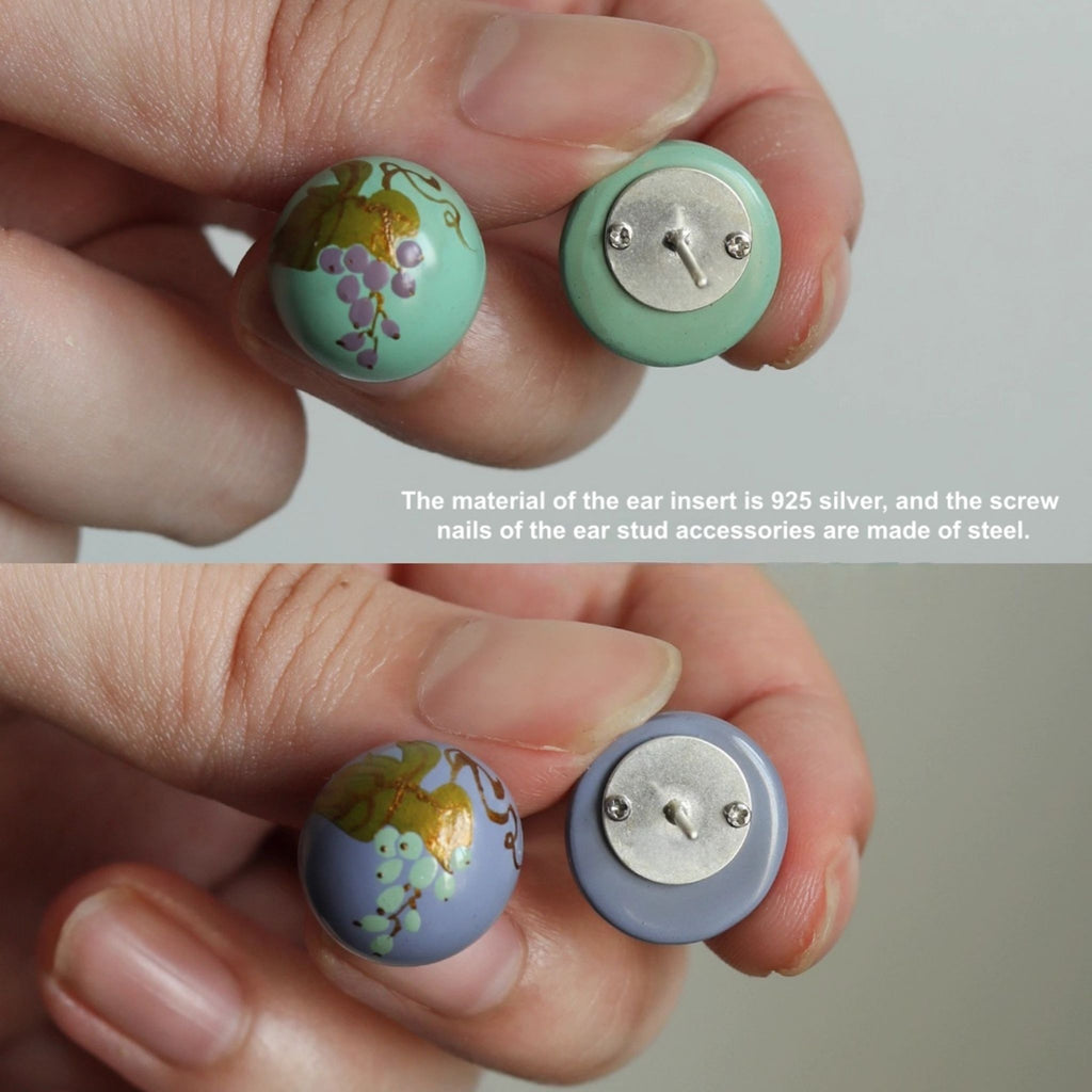 Close-up of two earrings with floral design and silver inserts held between fingers against a neutral background.