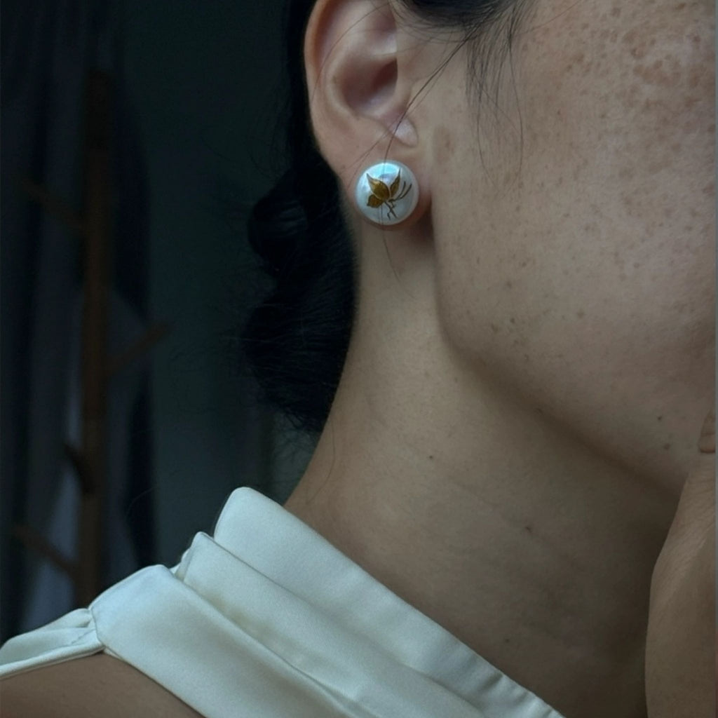 Close-up of a person wearing a floral earring with a blurred background