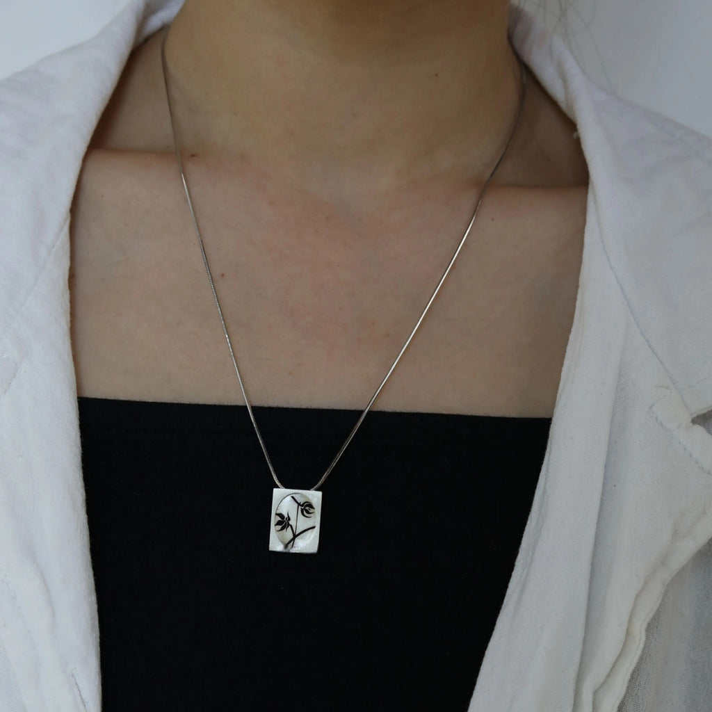 Necklace with a square pendant featuring a face design worn by a person. LacLume Starry Sky Cosmos Flower Necklace Hand-Painted Lacquer Dreamy Vibe