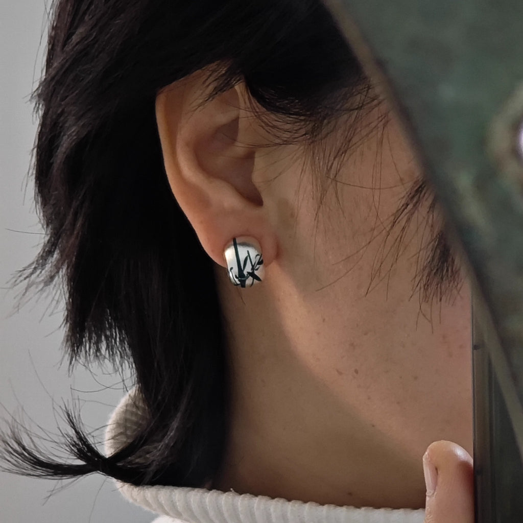 Close-up of an ear wearing a black and white patterned earring with blurred background