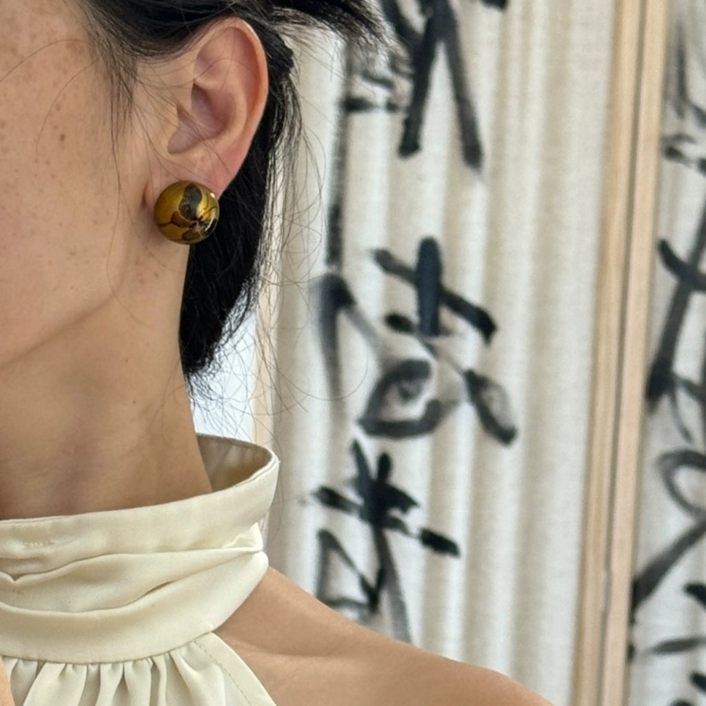 Close-up of a person wearing gold earrings with a blurred background LacLume HandPainted Retro Autumn Butterfly Earrings Luxe Artisanal Lacquer Jewelry