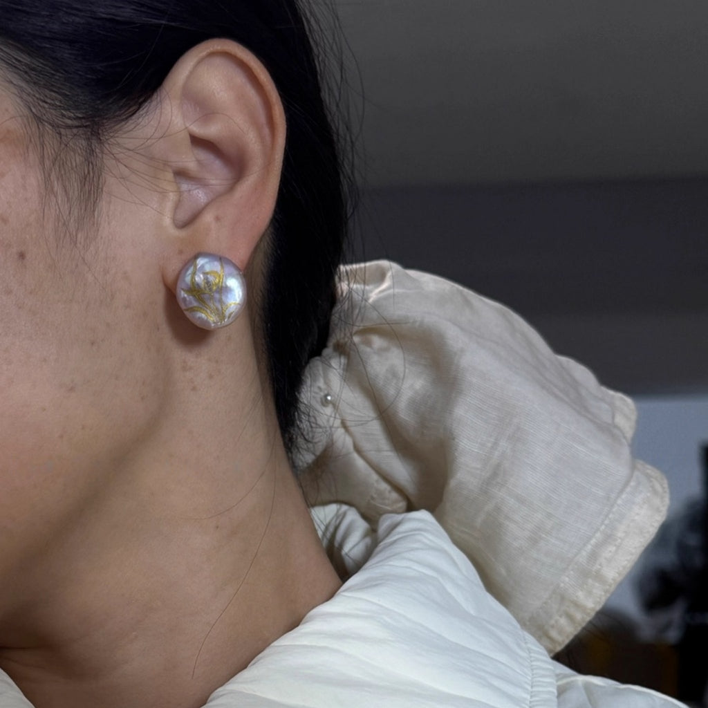 Close-up of a person wearing pearl earrings with a neutral background