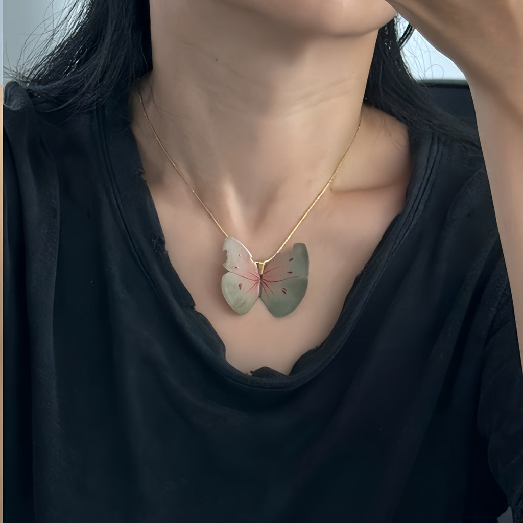 Butterfly-shaped pendant on a necklace worn by a person in a black top.