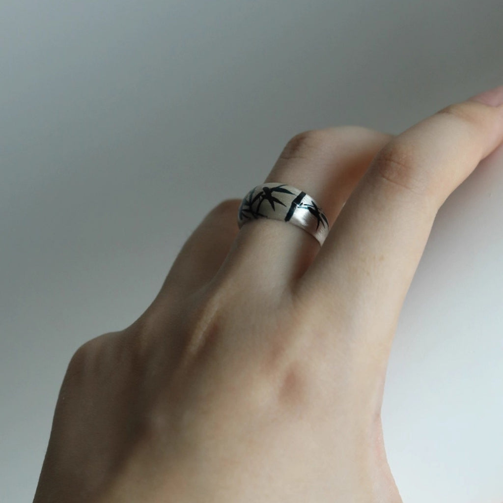 Hand wearing a silver ring with a subtle design on a neutral background