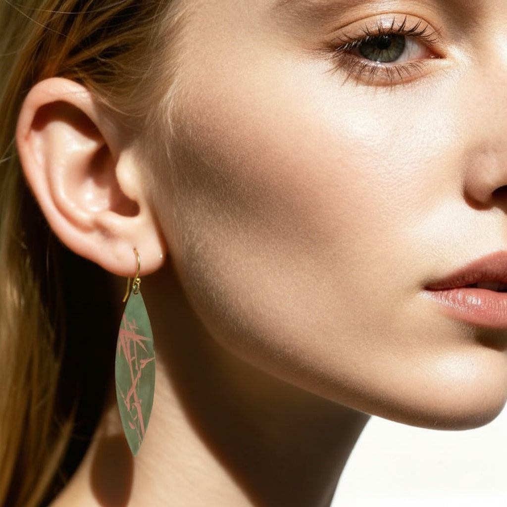 Close-up of a woman wearing a green leaf-shaped earring. LacLume Handcrafted Lacquer Jewelry Artisanal Bamboo Pattern Earrings Daily Wear Minimalist Look
