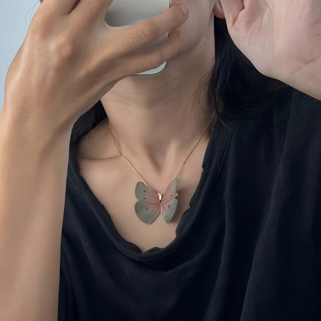 Person wearing a butterfly-shaped necklace with a plain background